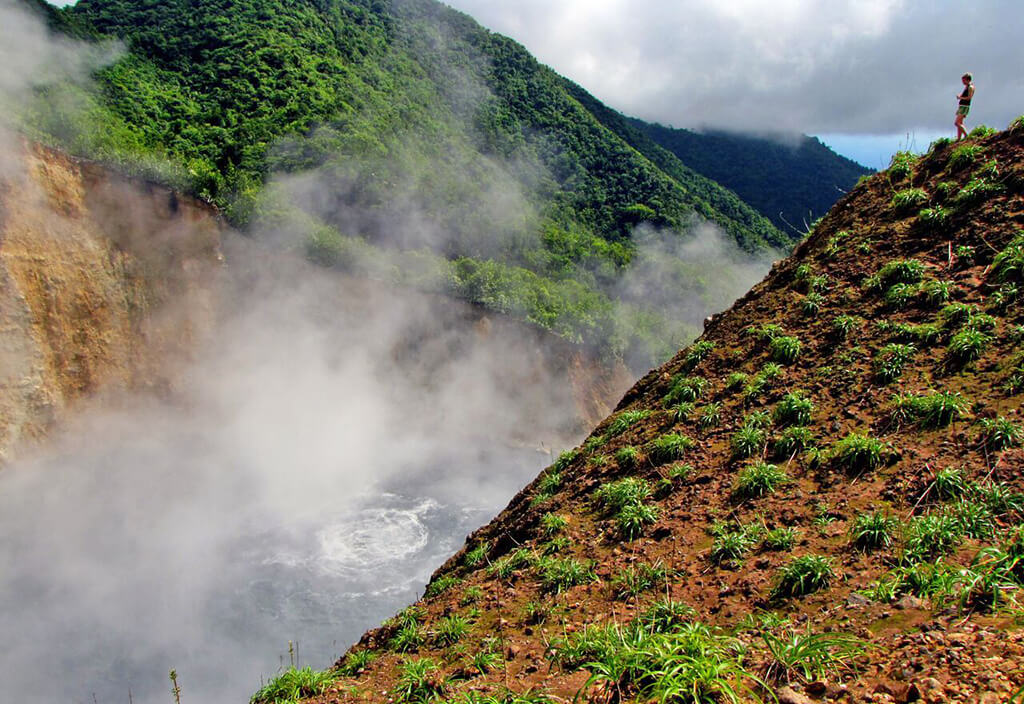 A hiker surveys the volcanic-heated waters of Boiling Lake.