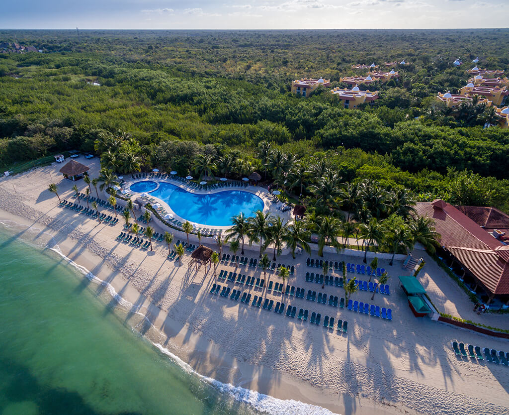 An aerial view of Occidental Cozumel resort, showing the Beach Club and the guest rooms tucked into the surrounding jungle.