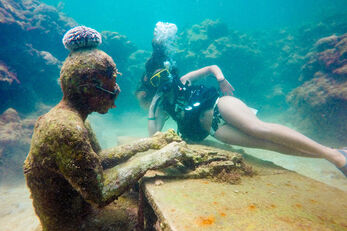 A diver poses with a figure at the island's underwater sculpture garden.